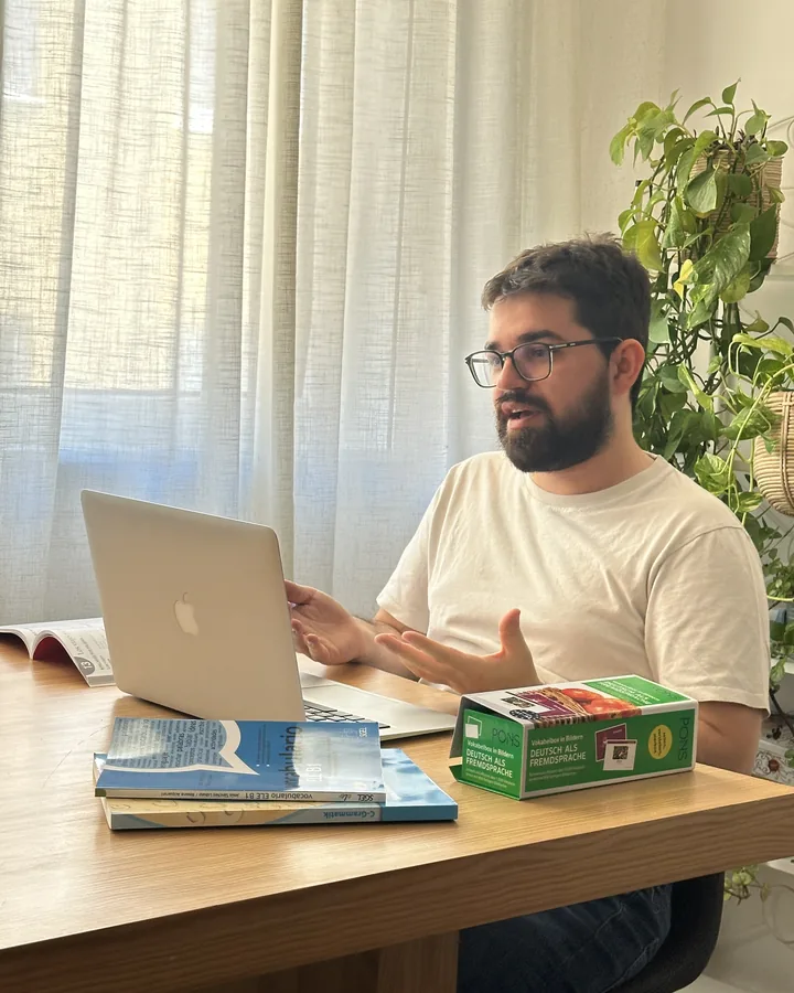 David dando clase por videollamada con sus libros de alemán